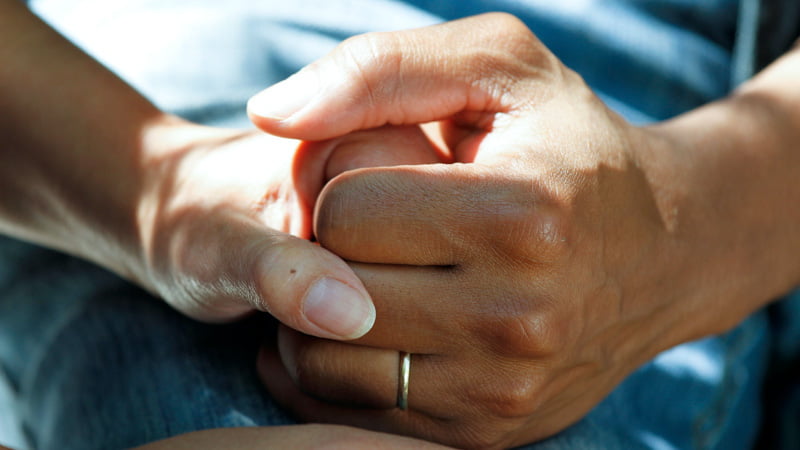 A person holding a cancer patient's hand 