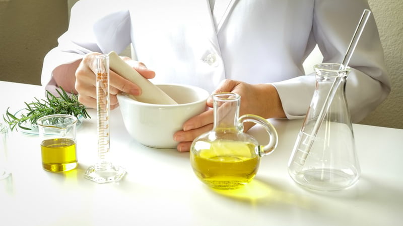 A female scientist working in a lab with hemp cbd oil and a hemp bud on the table