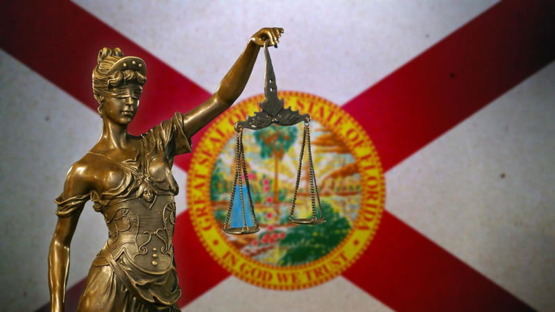 statue of Lady Justice in front of Florida state flag