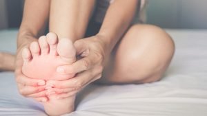 Person on bed holding foot due to pains caused by gout