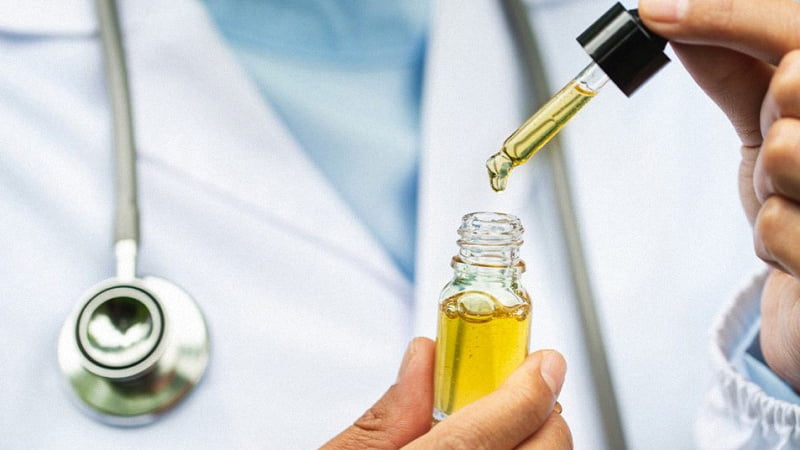 Doctor holding CBD oil bottle and dropper