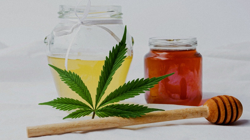 Hemp Flower and Honey in a Jar with Stick in a White Background