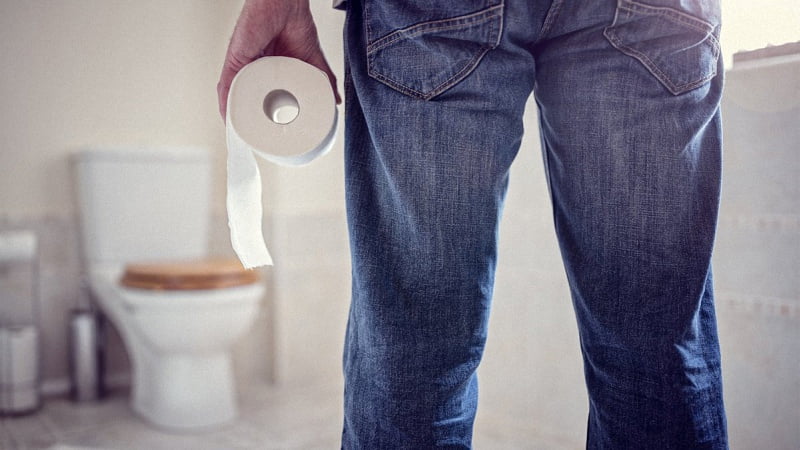 man holding toilet paper while facing the toilet