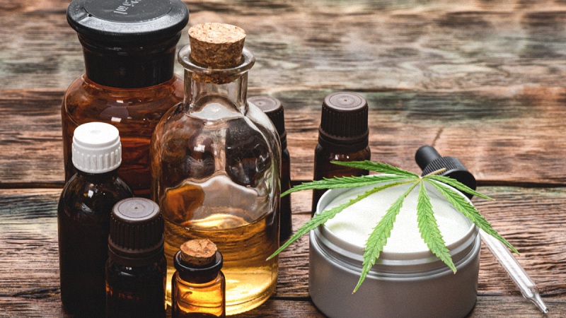 CBD Products with Hemp Leaf in a Wooden Background