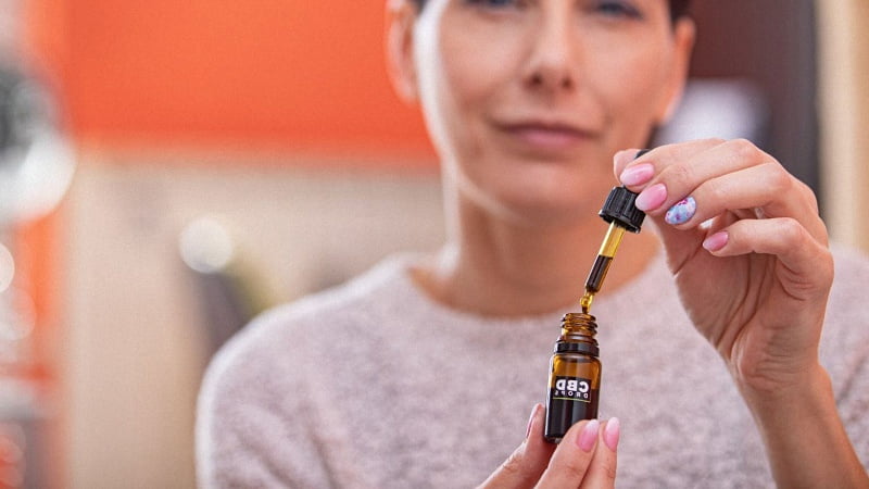 Woman holding CBD oil bottle and dropper