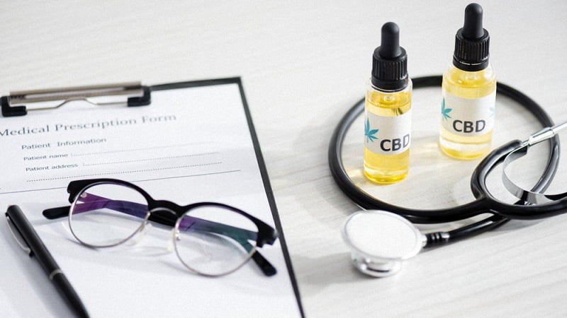 CBD Oil With Lettering Beside Stethoscope Paper Eyeglasses and Pen