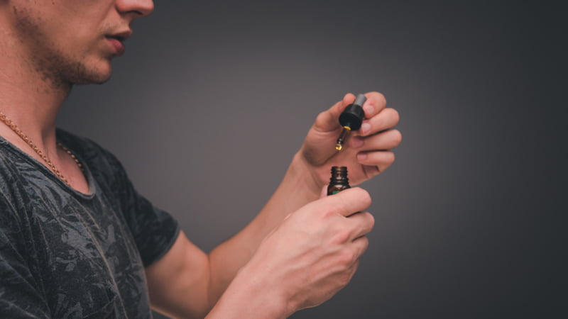 Young Person Wearing Black Holding CBD Oil